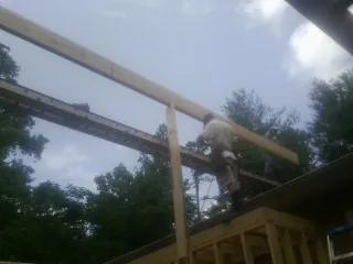 Carpenter setting a ridge beam over a new addition frame — Ice Dam Removal by Roofing Brothers in Overton