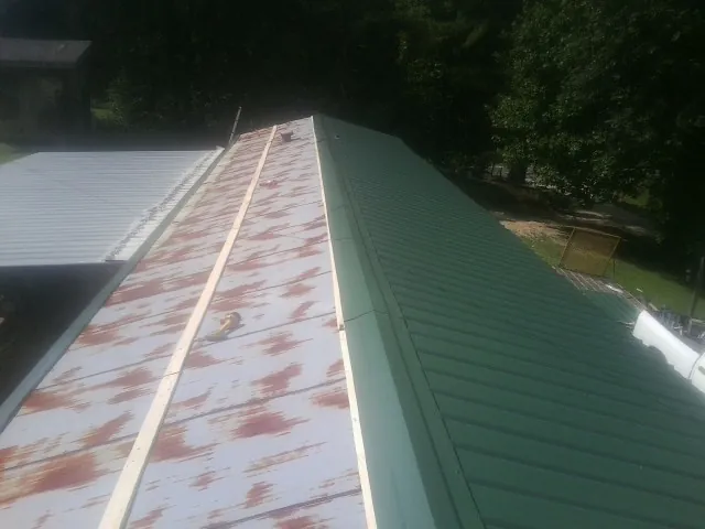 Old rusted panels beside newly installed green metal roofing — Wind Damage Roof Repair by Roofing Brothers in Overton