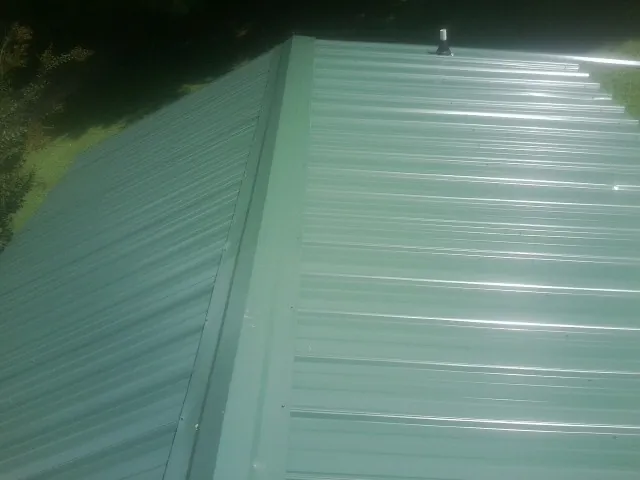 New green metal panels meeting at the ridge of a roof — Flat Roof Repair work by our crew in Overton