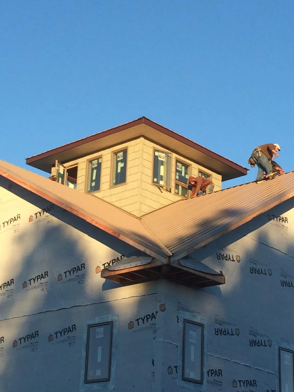 Roofers working around a rooftop cupola on a new metal roof at sunset — Roof Waterproofing in Overton by Roofing Brothers